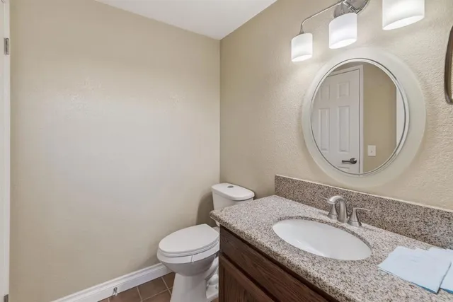 a bathroom with a granite countertop toilet a sink and a mirror