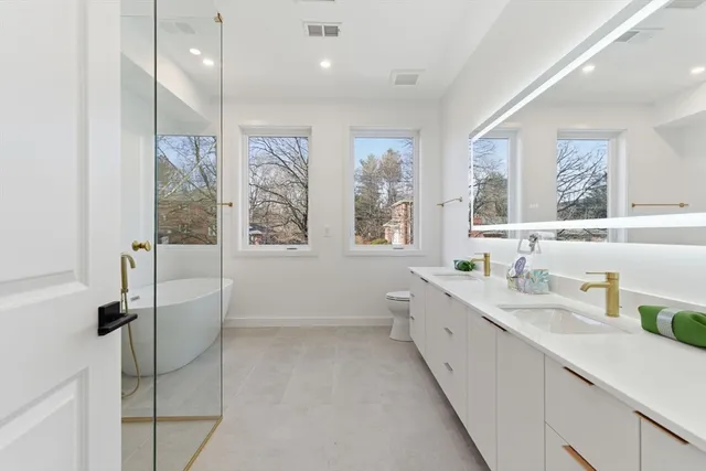 a bathroom with a double vanity sink toilet mirror and tub