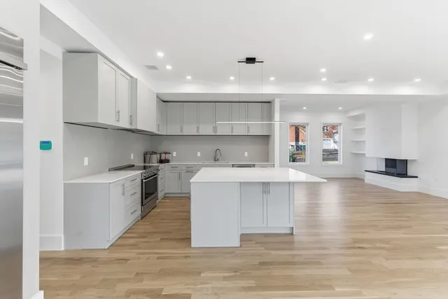a large white kitchen with kitchen island a sink a stove and a refrigerator