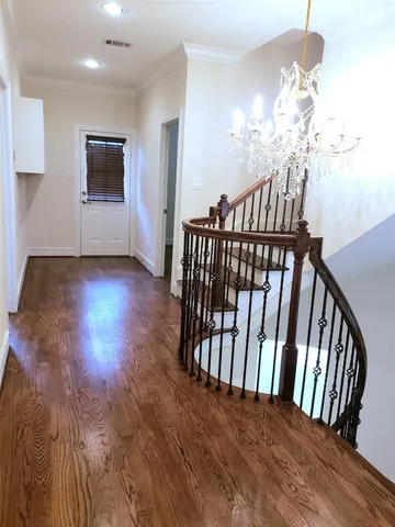 a view of a hallway with wooden floor and chandelier