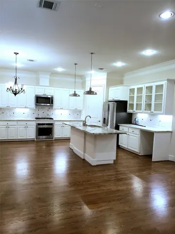 a large kitchen with kitchen island a stove a sink a refrigerator and a dining table with wooden floor