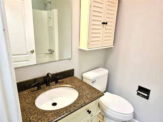 a bathroom with a granite countertop toilet a sink and a mirror