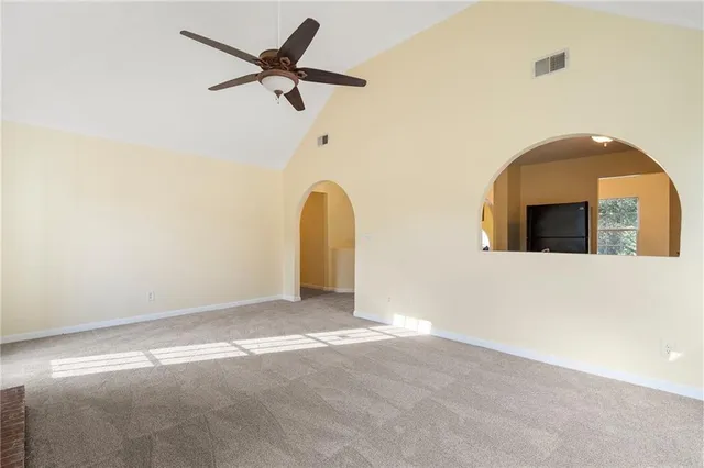 an empty room with windows and chandelier fan