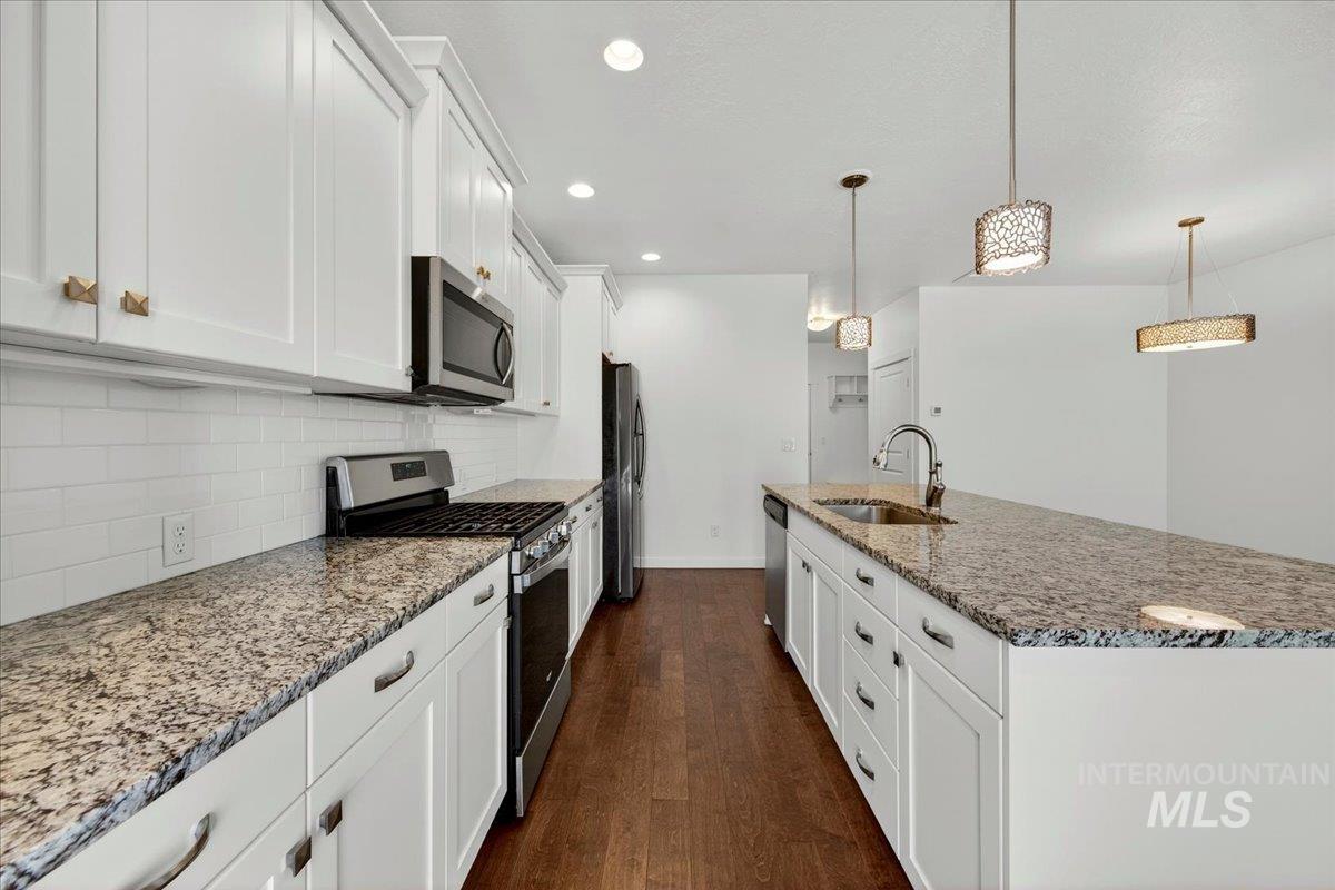 4204 East Silverking Lane Meridian, ID 83642 - Photo 14 of 40 Modern kitchen featuring white shaker cabinetry, stainless steel appliances, granite countertops, and wood-finish flooring