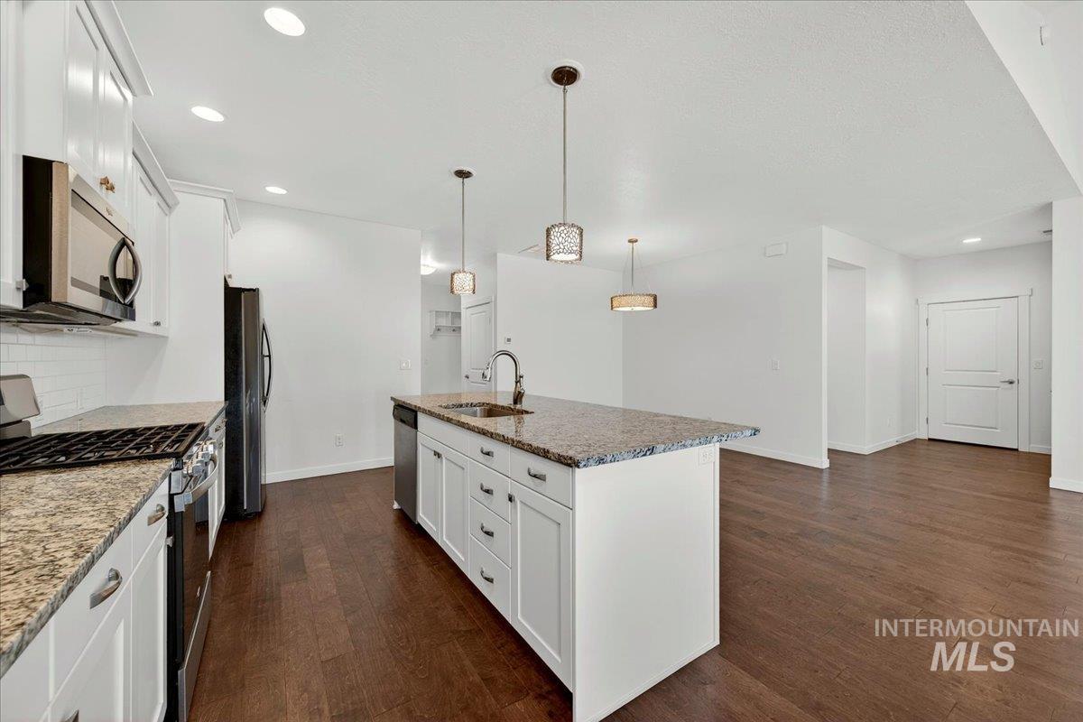 4204 East Silverking Lane Meridian, ID 83642 - Photo 15 of 40 Kitchen with a central island featuring a stainless steel sink, a gooseneck faucet, and stone countertops