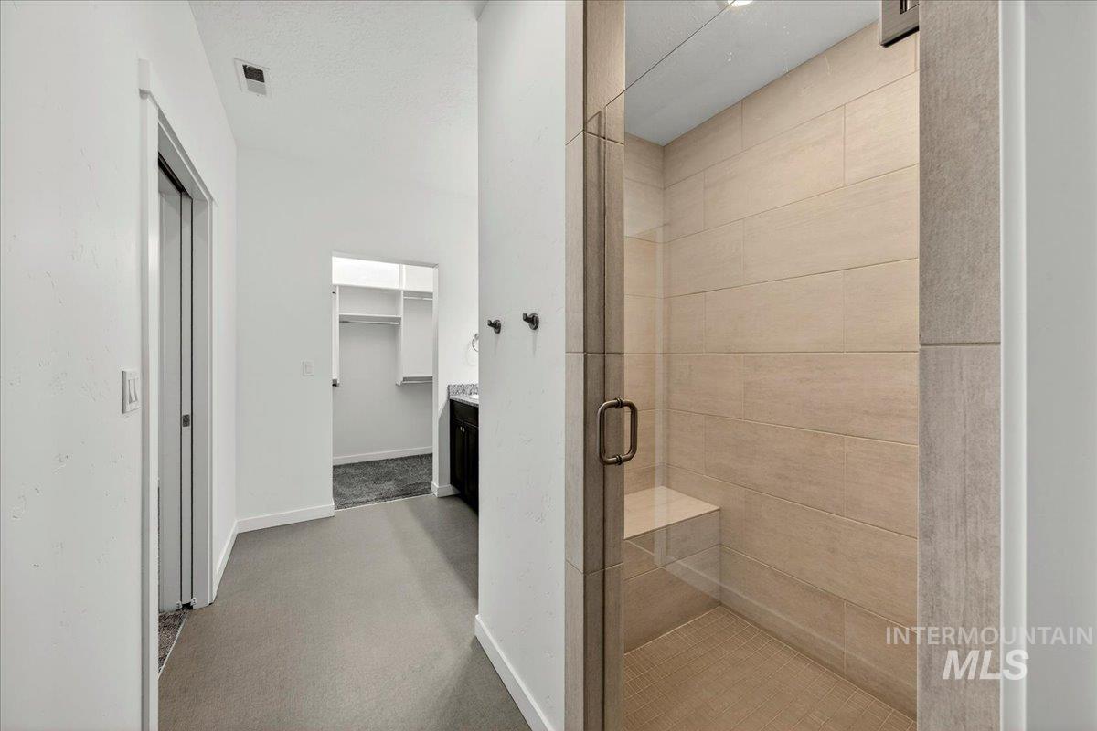 4204 East Silverking Lane Meridian, ID 83642 - Photo 28 of 40 Walk-in shower featuring a glass enclosure, light-toned tile, and a built-in bench