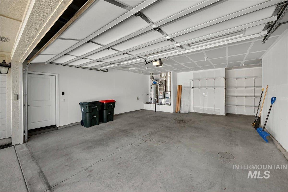 4204 East Silverking Lane Meridian, ID 83642 - Photo 31 of 40 Spacious garage featuring a concrete floor, overhead lighting, an interior access door, a tank-style water heater, and built-in shelving