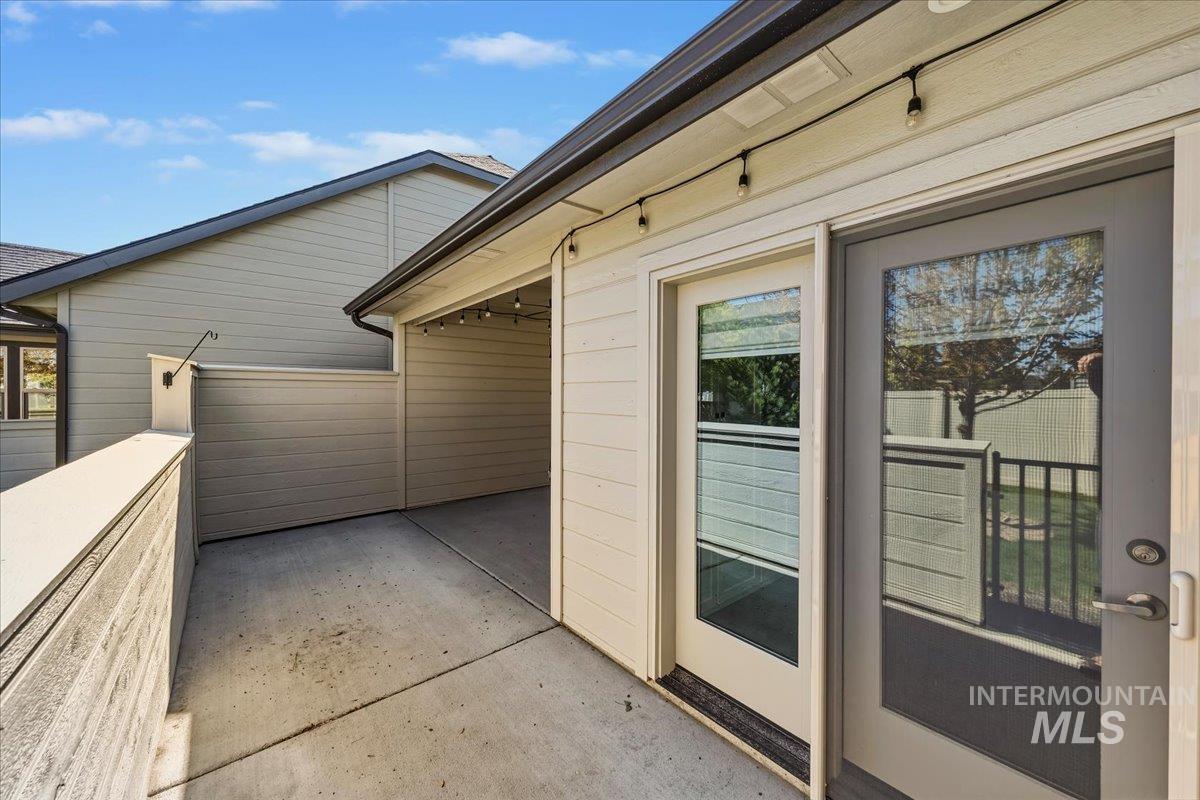 4204 East Silverking Lane Meridian, ID 83642 - Photo 32 of 40 Concrete patio area with a privacy wall, string lighting, and two glass-paneled doors