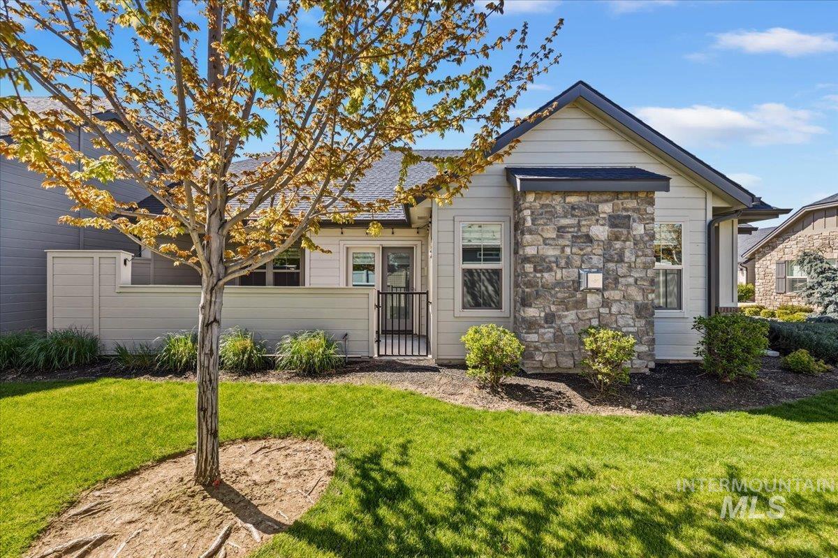 4204 East Silverking Lane Meridian, ID 83642 - Photo 36 of 40 Contemporary exterior featuring light-toned siding, a stone accent column, dark trim, and a dark shingle roof