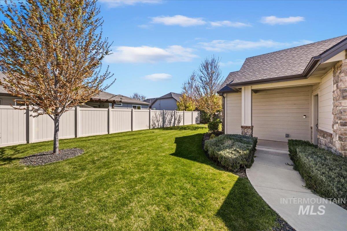 4204 East Silverking Lane Meridian, ID 83642 - Photo 38 of 40 Manicured lawn with a young tree, concrete pathway, and mature shrubbery