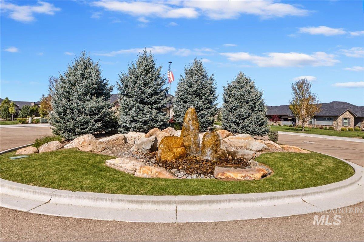 4204 East Silverking Lane Meridian, ID 83642 - Photo 39 of 40 Central roundabout featuring a stone water feature, mature evergreen trees, and manicured landscaping