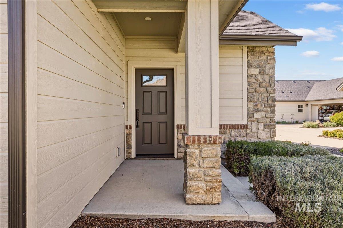 4204 East Silverking Lane Meridian, ID 83642 - Photo 4 of 40 Entryway featuring stone veneer accents, horizontal siding, a dark paneled door with glass insert, and a covered porch