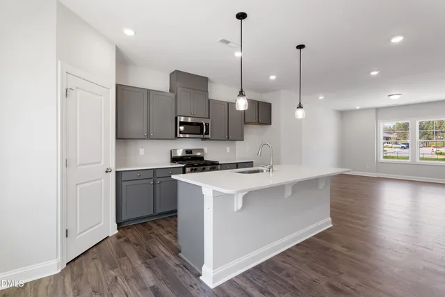 a kitchen with kitchen island a sink stainless steel appliances and wooden floor