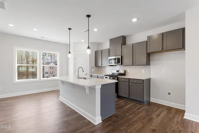 a kitchen with stainless steel appliances granite countertop a sink a stove a refrigerator and a microwave