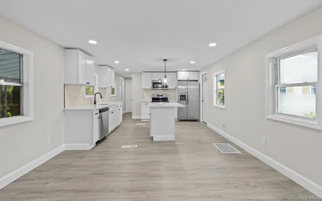 a large white kitchen with lots of counter top space and stainless steel appliances