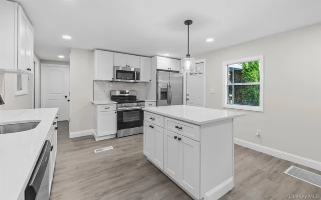 a kitchen with white cabinets and stainless steel appliances