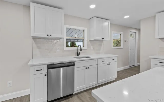 a kitchen with white cabinets appliances and a sink