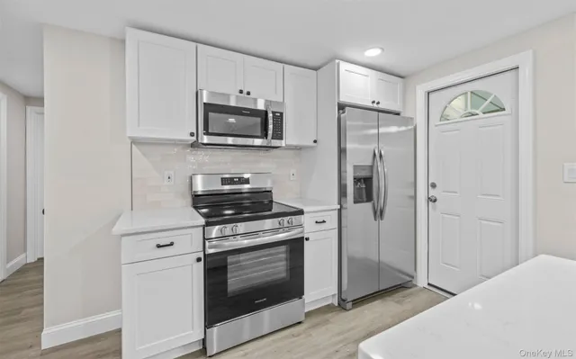 a kitchen with stainless steel appliances white cabinets and a stove top oven