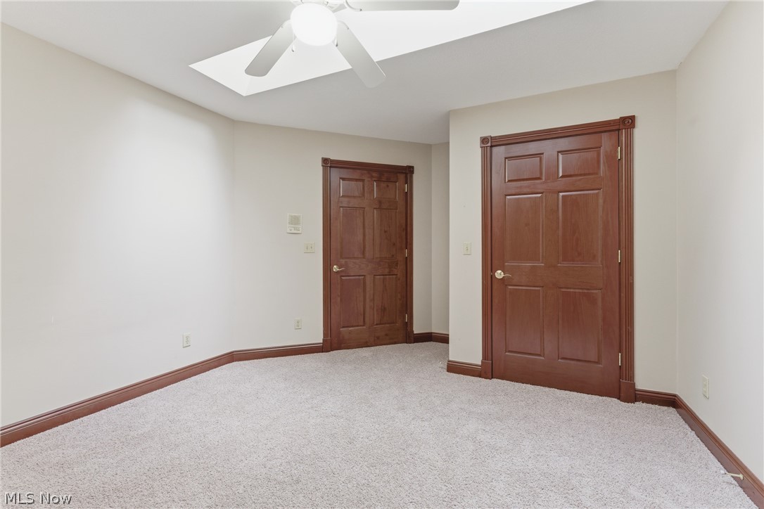 2184 Brenner Road Northeast Carrollton, OH 44615 - Photo 23 of 50 Room featuring light-colored carpeting, two paneled wood doors with matching trim, a ceiling fan, and a skylight