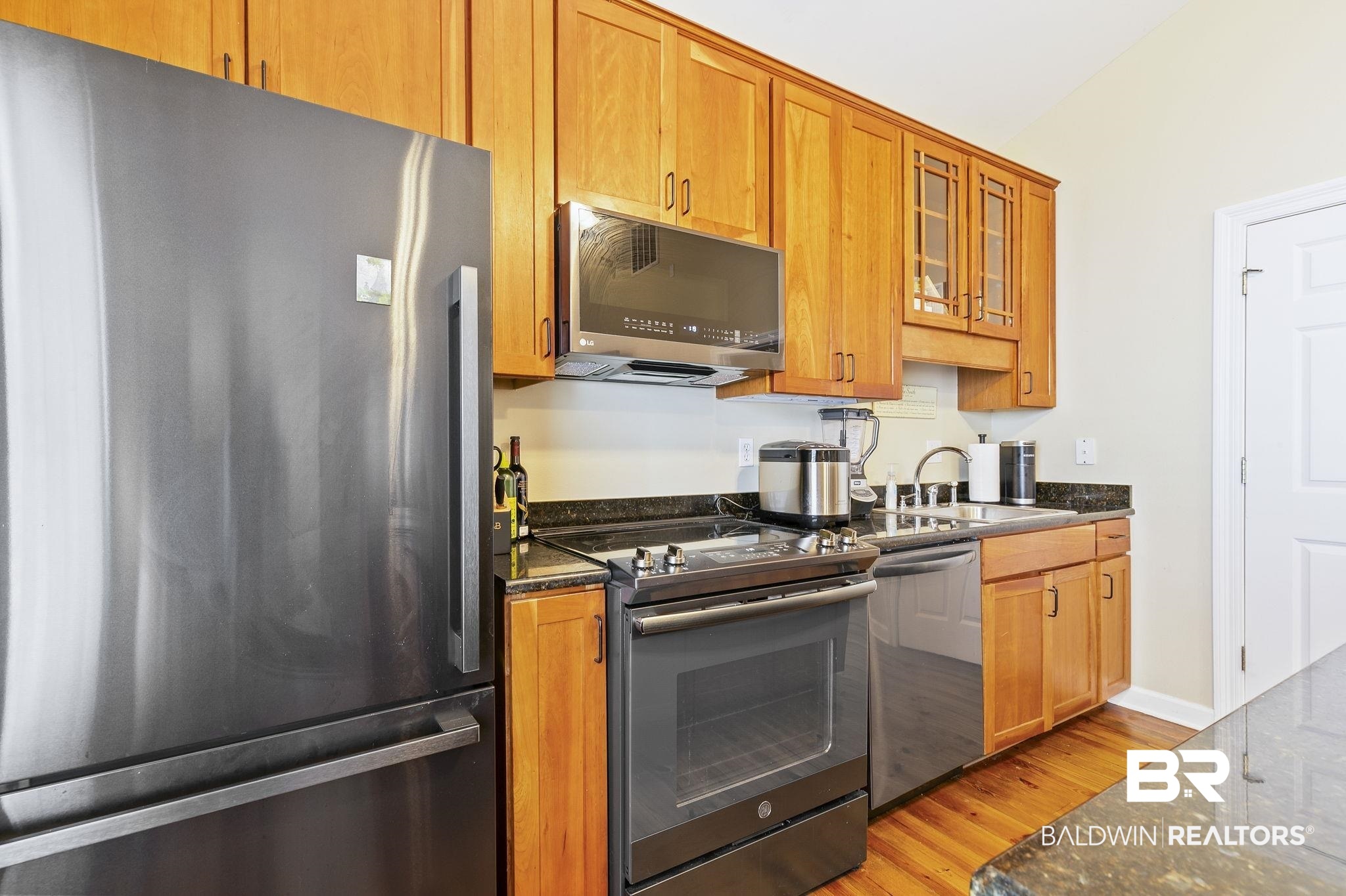 17341 Cabin Road Loxley, AL 36551 - Photo 21 of 49 Kitchen with dark stone counters, light wood-type flooring, appliances with stainless steel finishes, sink, and vaulted ceiling