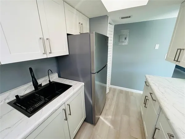 a kitchen with stainless steel appliances granite countertop a refrigerator a sink and white cabinets