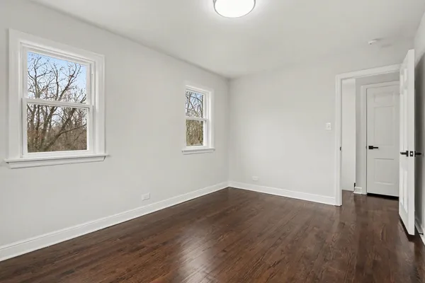a view of a big room with wooden floor and windows