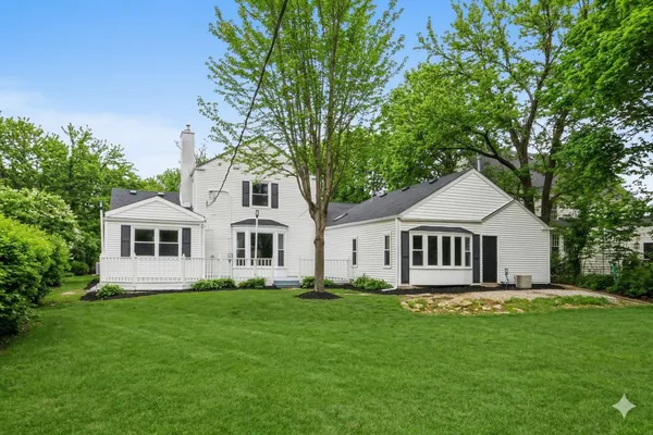 a front view of a house with a garden and trees