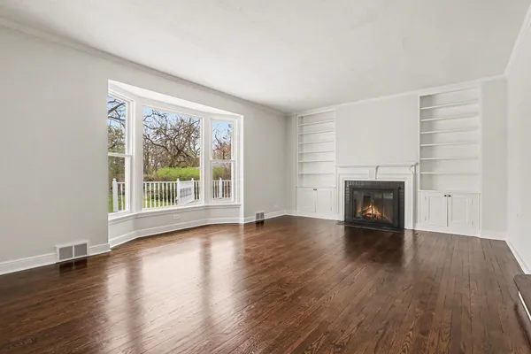 a view of empty room with wooden floor and fireplace