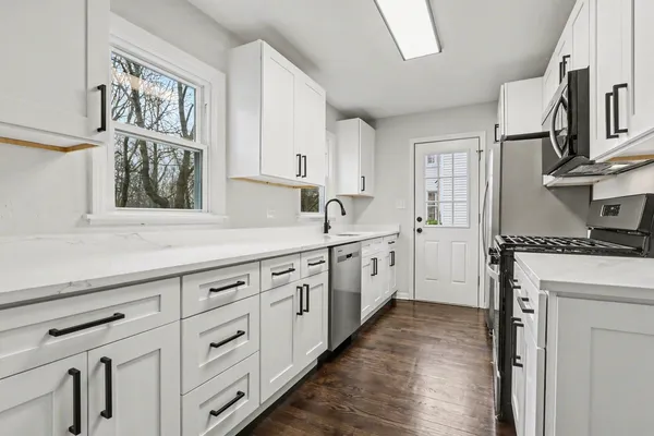 a kitchen with granite countertop white cabinets and white appliances
