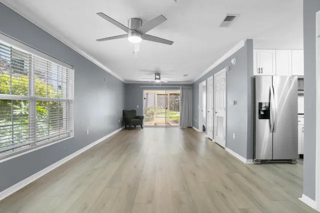 a view of a livingroom with wooden floor a ceiling fan and windows
