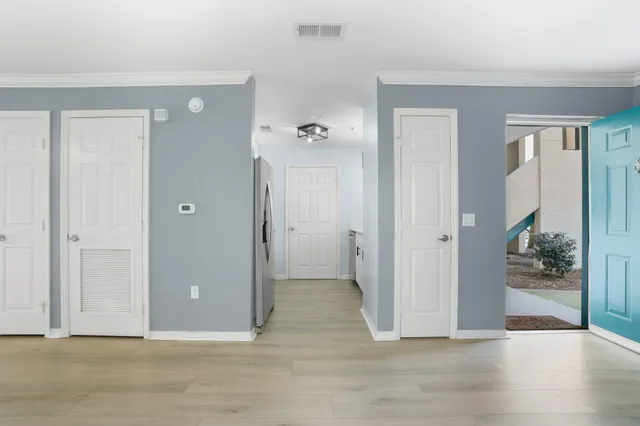 a view of a hallway with wooden floor and a bathroom