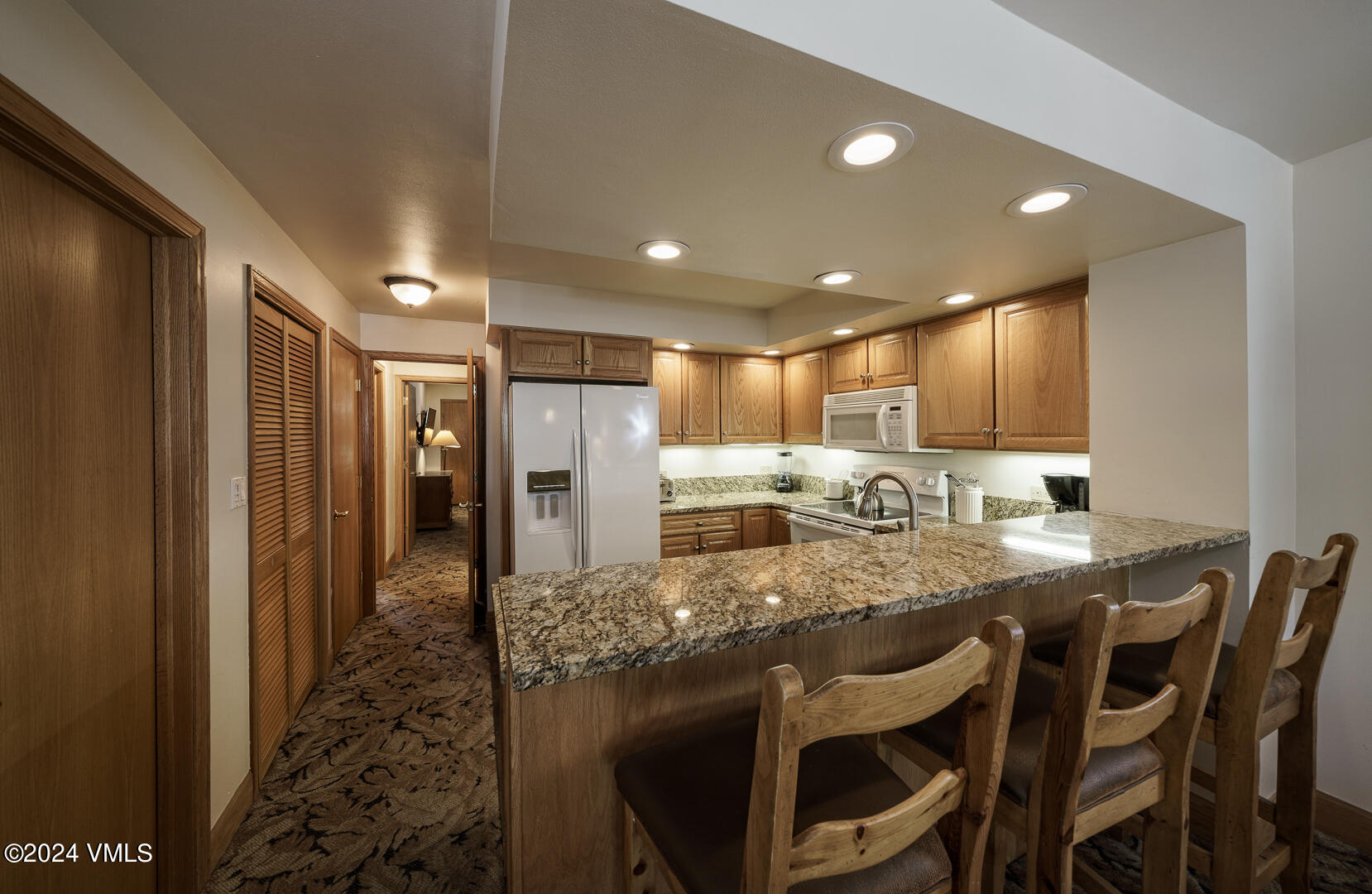 707 West Lionshead Circle, Unit 118 Vail, CO 81657 - Photo 13 of 29 a kitchen with kitchen island granite countertop wooden cabinets and refrigerator