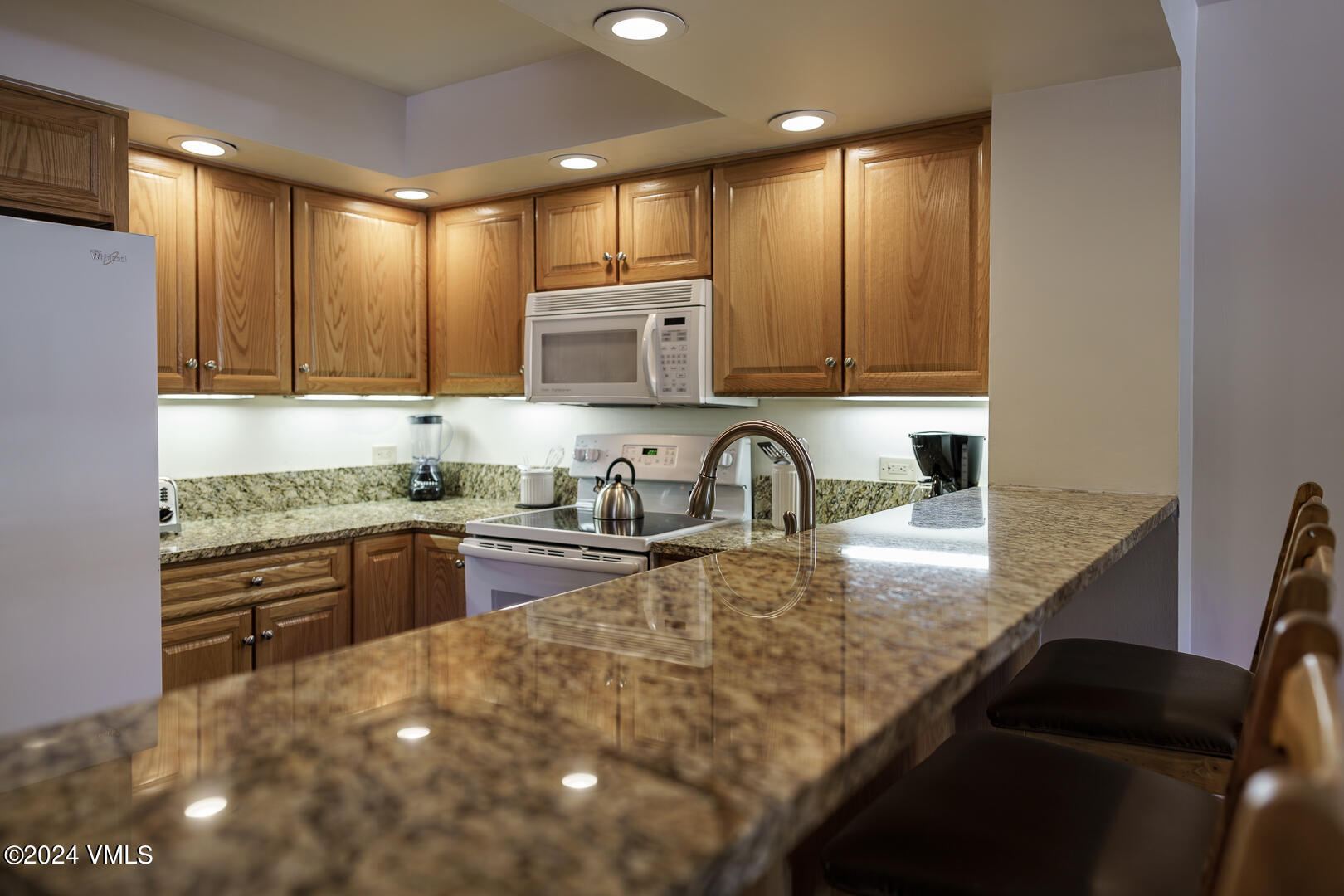 707 West Lionshead Circle, Unit 118 Vail, CO 81657 - Photo 15 of 29 a kitchen with kitchen island granite countertop a sink stove and cabinets