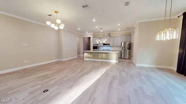 a view of a kitchen with granite countertop cabinets a counter top space stainless steel appliances and a chandelier