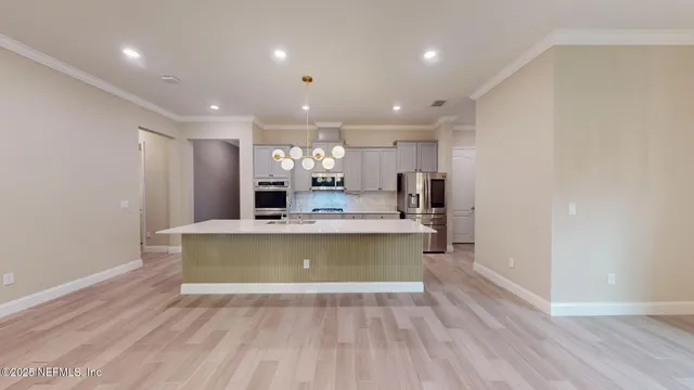 a large kitchen with stainless steel appliances a large counter top a stove and a refrigerator