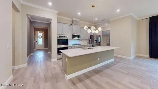 a large kitchen with stainless steel appliances a large counter top a stove and a refrigerator