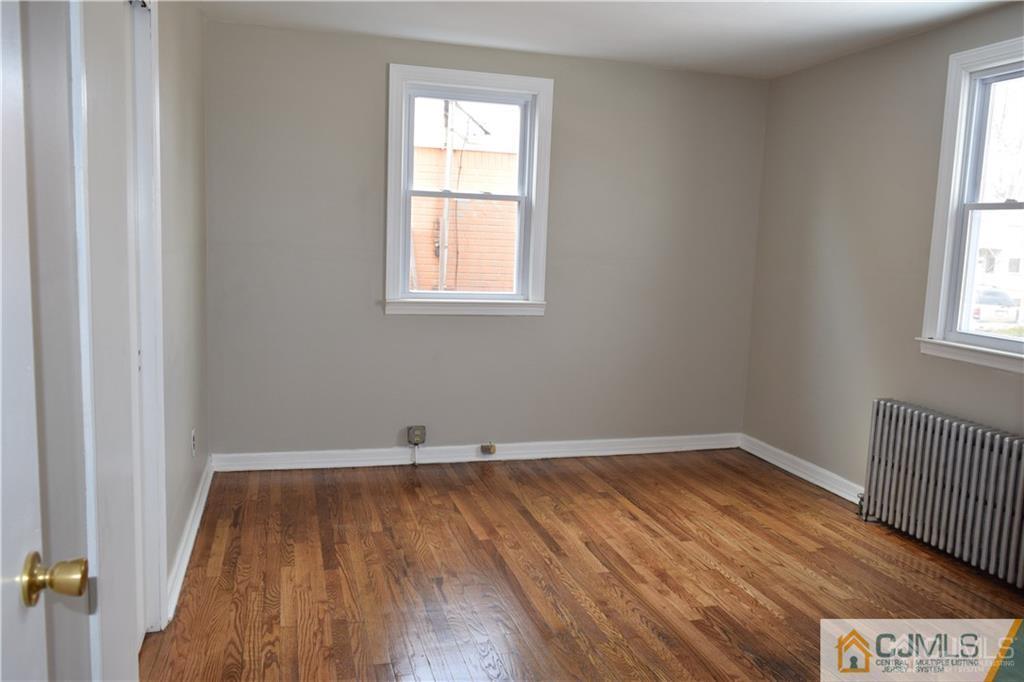 90 Holly Street, Unit 2 Port Reading, NJ 07064 - Photo 4 of 8 an empty room with wooden floor and windows