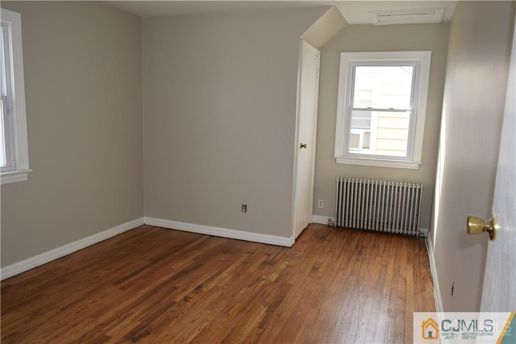 90 Holly Street, Unit 2 Port Reading, NJ 07064 - Photo 6 of 8 an empty room with wooden floor and windows