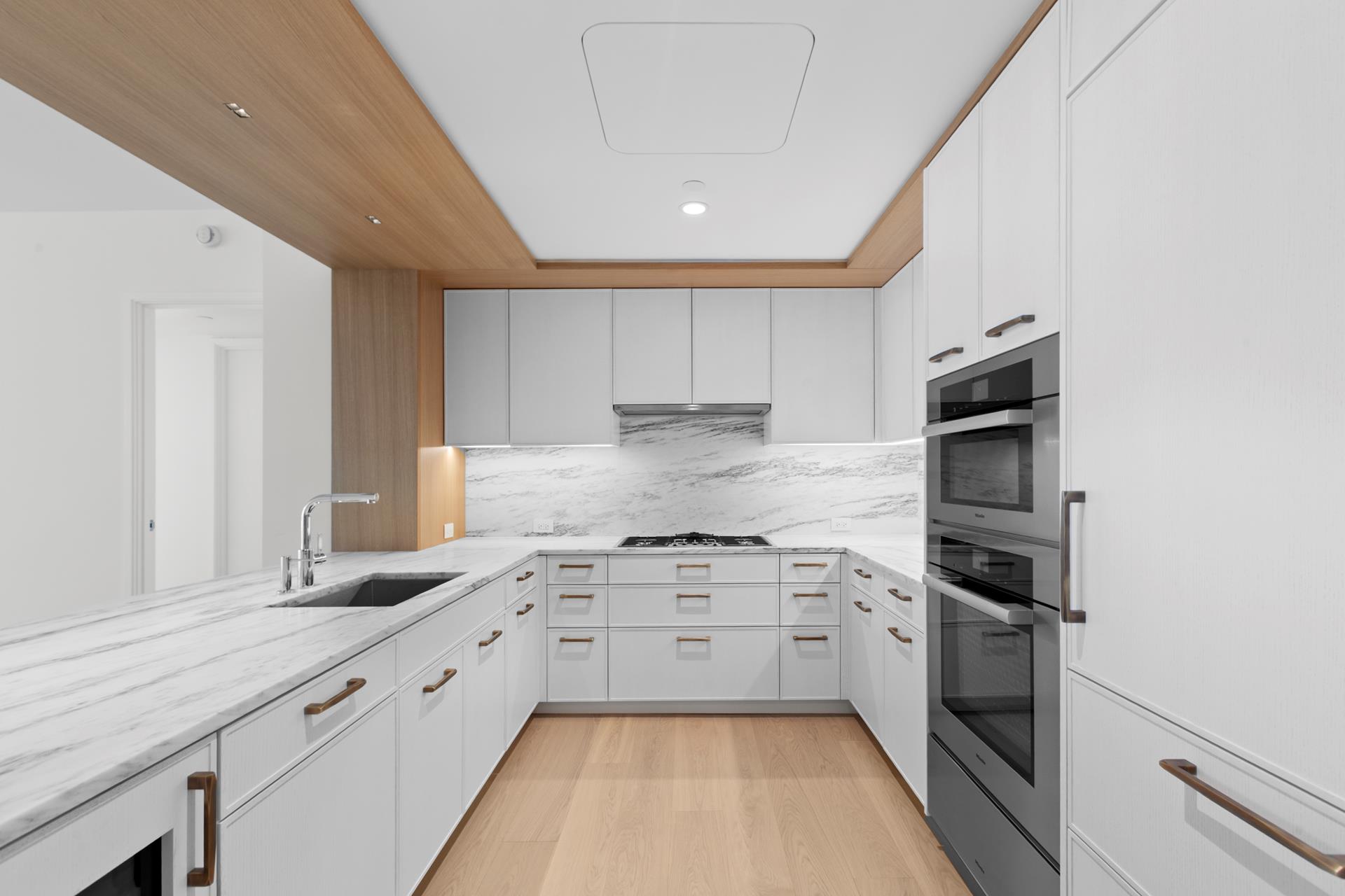 50 West 66th Street, Unit 15E Manhattan, NY 10023 - Photo 6 of 12 a kitchen with granite countertop white cabinets and stainless steel appliances