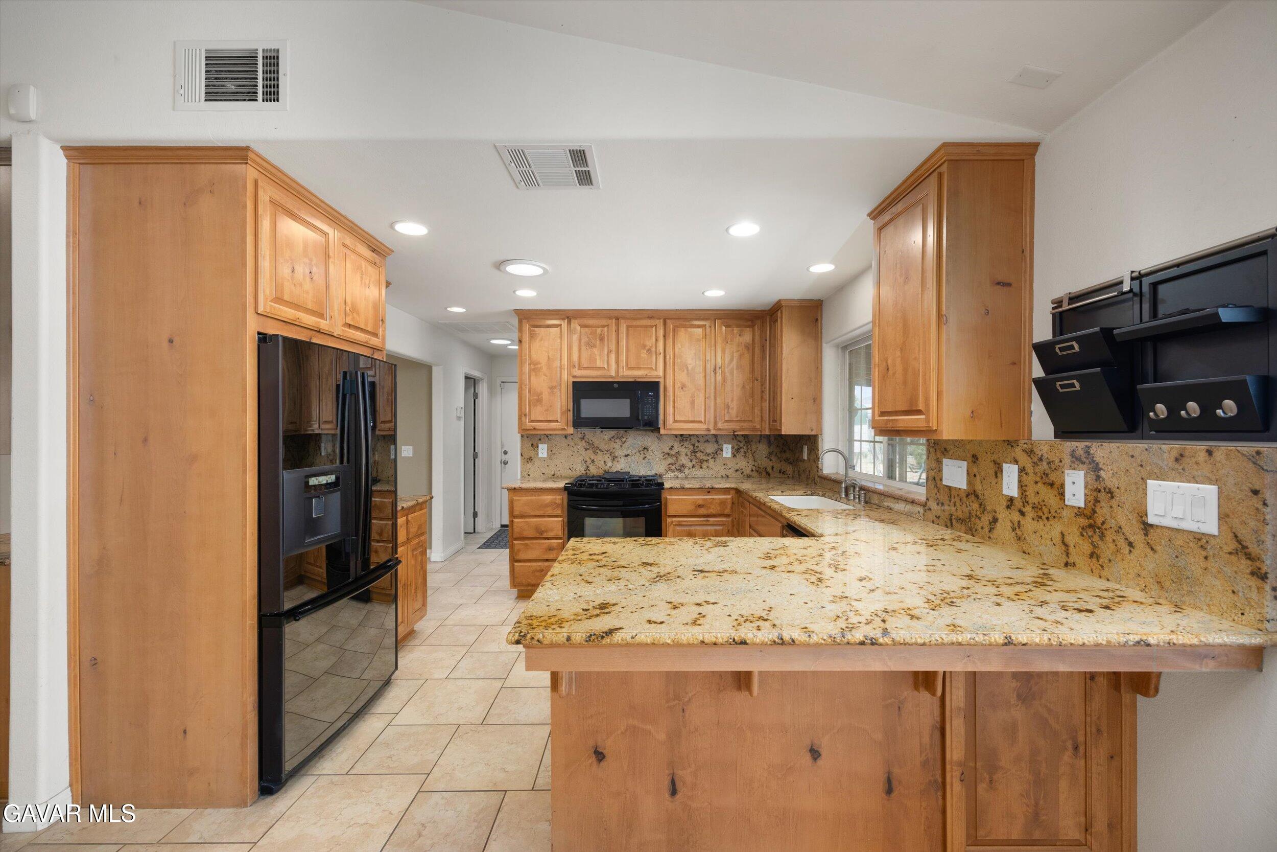 4961 Montiverde Road Mojave, CA 93501 - Photo 19 of 57 a kitchen with kitchen island granite countertop a large counter top stainless steel appliances and cabinets