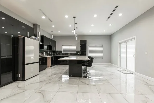 a kitchen with stainless steel appliances kitchen island granite countertop a refrigerator and chairs