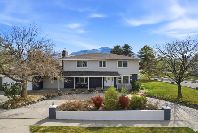12021 Misty Sea Road Riverton, UT 84065 - Photo 1 of 1 Traditional home with covered porch, a mountain view, a chimney, a front lawn, and stucco siding