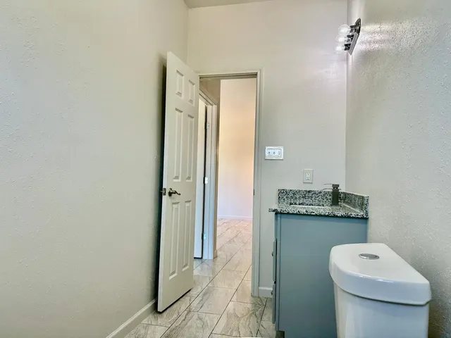 a bathroom with a granite countertop sink a toilet and shower