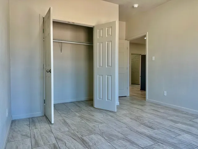 a view of an empty room with wooden floor and closet area
