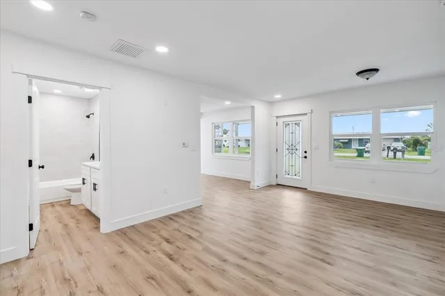 a view of an empty room with wooden floor and a window