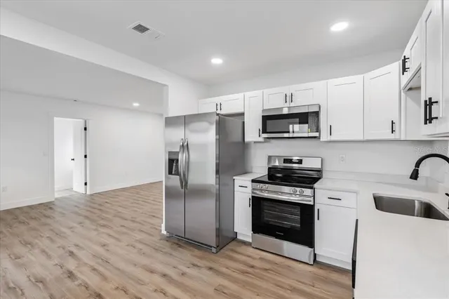 a kitchen with a sink stainless steel appliances and white cabinets