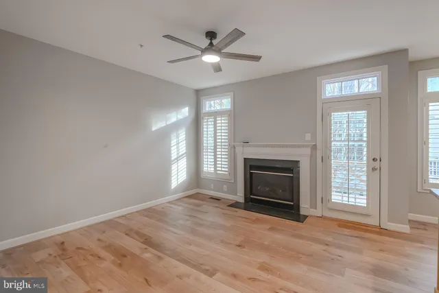 a view of an empty room with wooden floor fireplace and a window