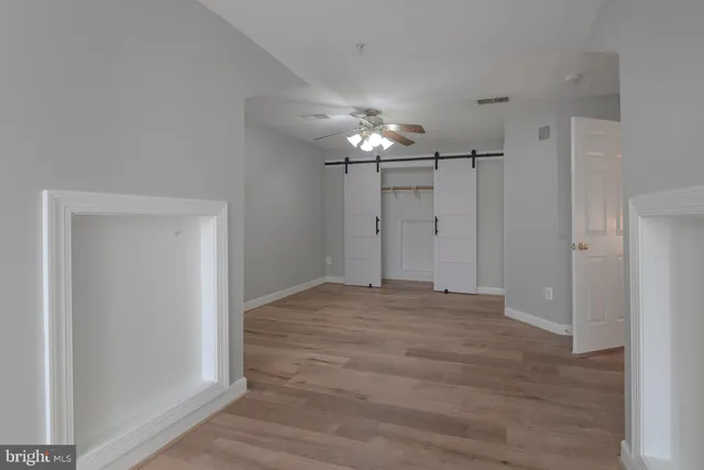 a view of an empty room with wooden floor and chandelier