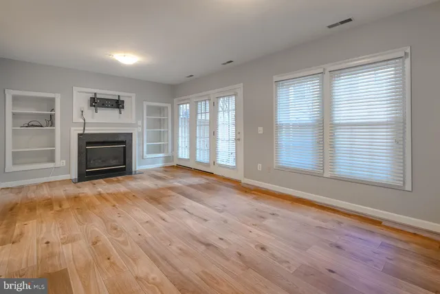 an empty room with windows fireplace and cabinet