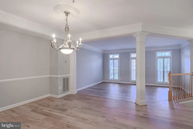 a view of an empty room with wooden floor and chandelier